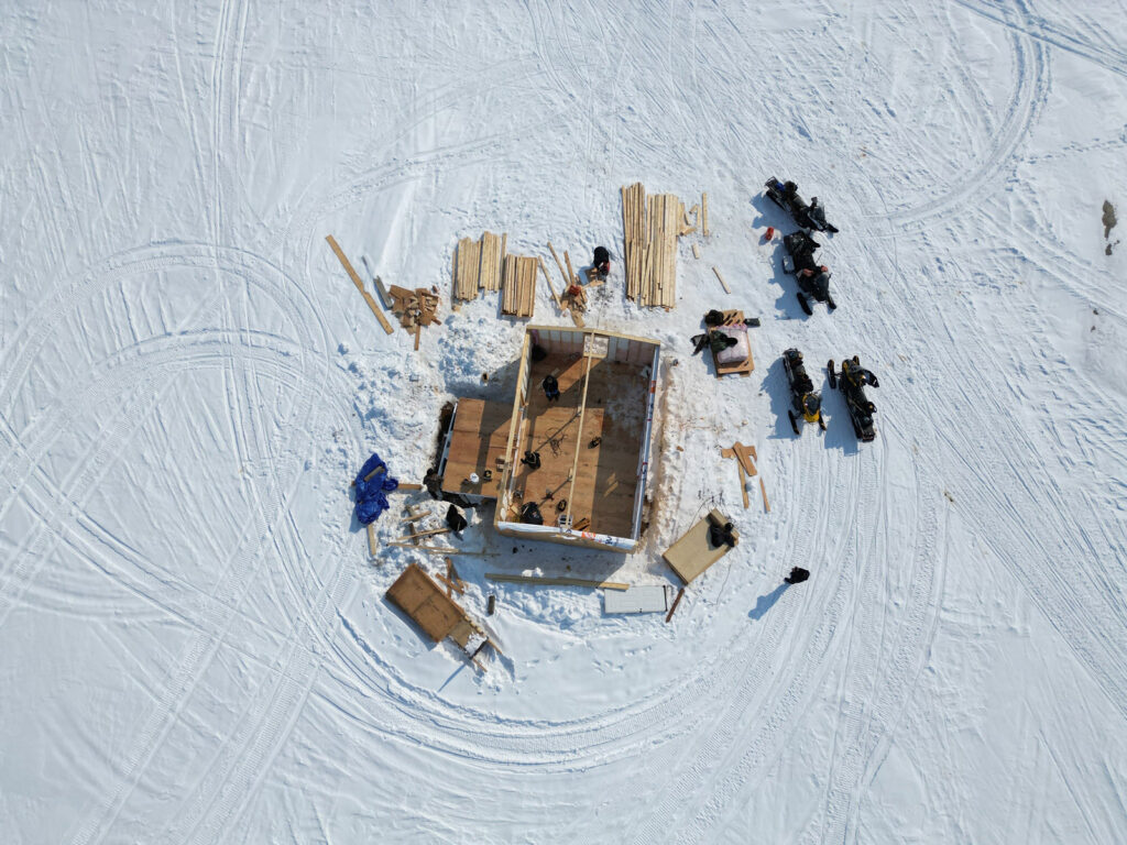 Aerial view of cabin being built on snowy landscape